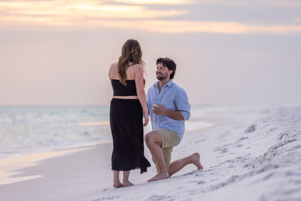 man kneeling to propose to his girlfriend on the beach at sunset in Grayton Beach State Park.