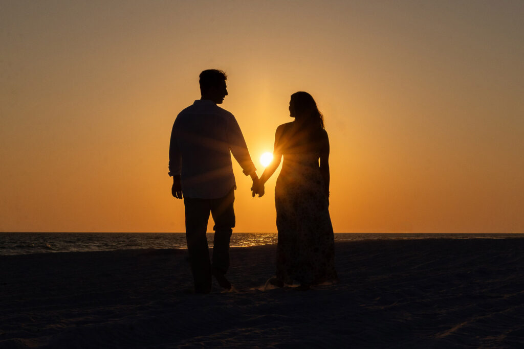 a silhouette photo of a newly engaged couple walking toward the sun and Gulf on 30a.