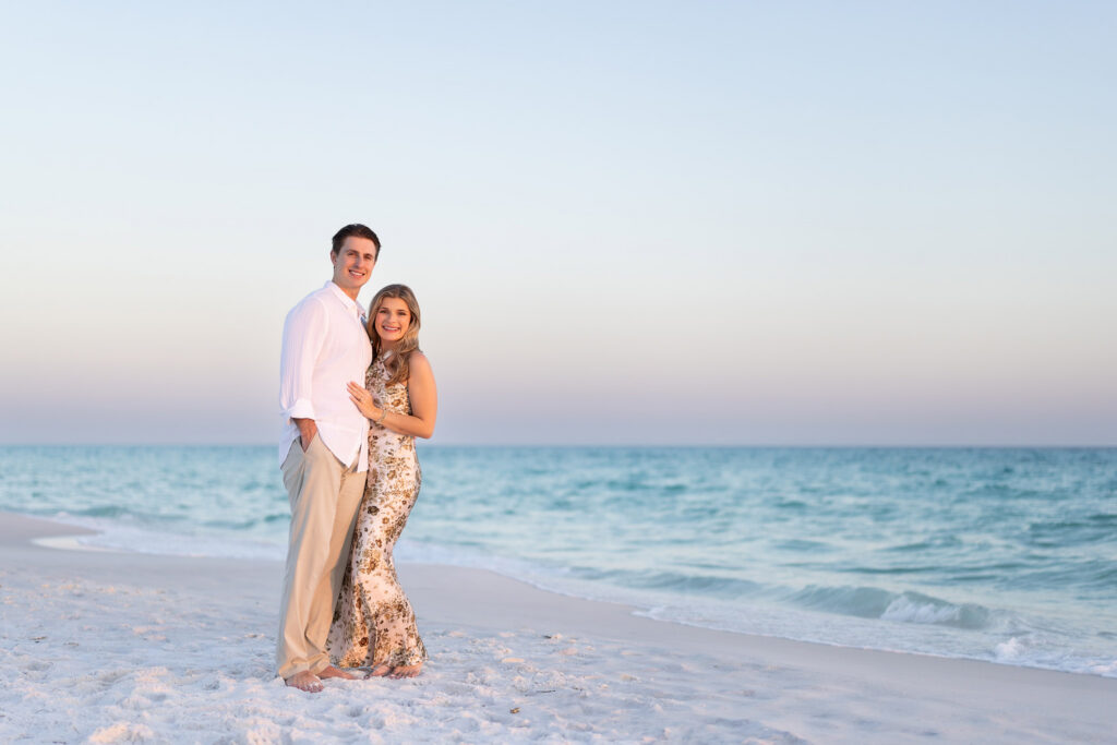 newly engaged couple posing for a shot on the beach at sunset on 30a beach.
