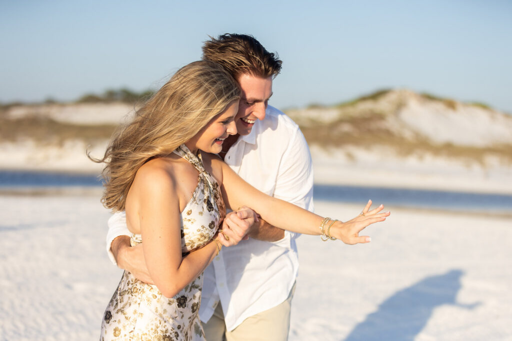 Surprise proposal on white sand beach along 30A Florida and the girlfriend is admiring her ring.