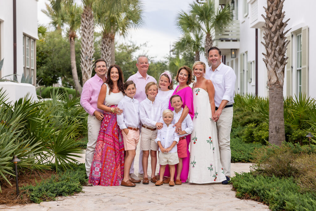 A family of 11 wearing fuscia and neutrals posing for their photo at Alys beach on 30a.